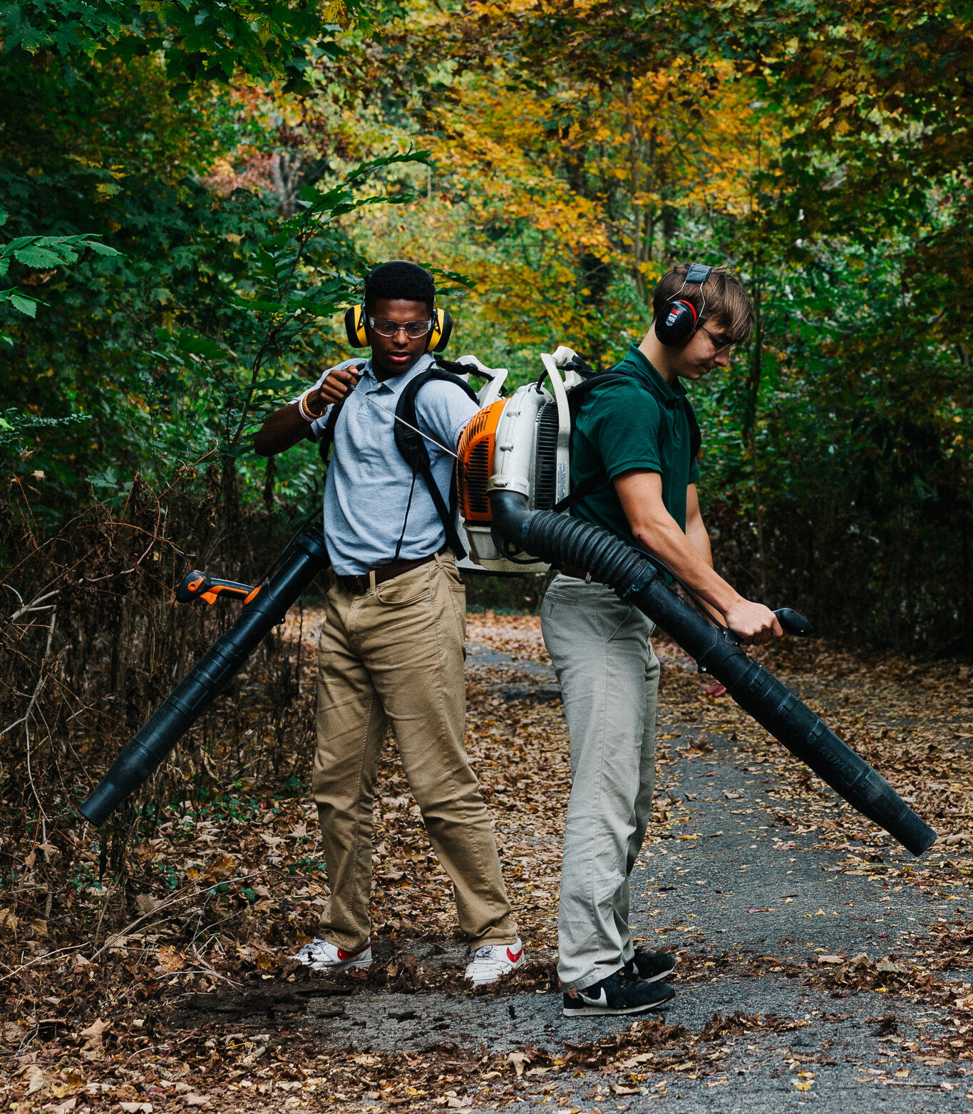 two students blowing off leaves